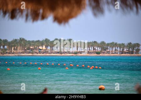 Boe gialle galleggianti sulla superficie del mare come indicatore per la restrizione di nuoto in acque profonde presso il resort tropicale con vista della linea costiera in lontananza. Umano li Foto Stock