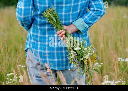 Bouquet di fiori selvatici in mani di donna, nascosto dietro la schiena Foto Stock