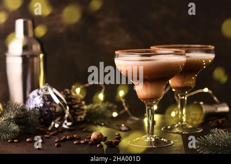 Cocktail Alexander in bicchiere da cocktail su tavolo di legno con shaker, noce moscata e piccolo grattugia con decorazioni natalizie su sfondo scuro. Fotografia delle bevande Foto Stock