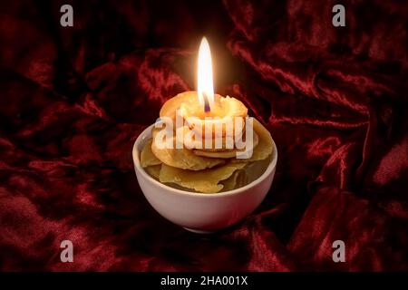 Candela di cera naturale a forma di rosa su sfondo velluto rosso Foto Stock