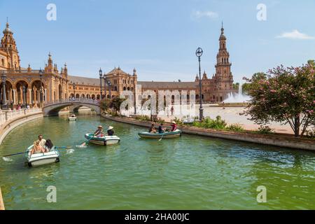 Siviglia, Andalusia, Spagna - 12 agosto 2021: Edificio rinascimentale centrale in piazza Plaza de Espana, vista sul fiume Guadalquivir con barche e gente Foto Stock