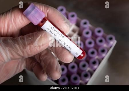 WHO covid-19 SARS varianti di preoccupazione o interesse di coronavirus, campione di sangue risultato positivo per variante tenuto in mano guanto lattice Foto Stock