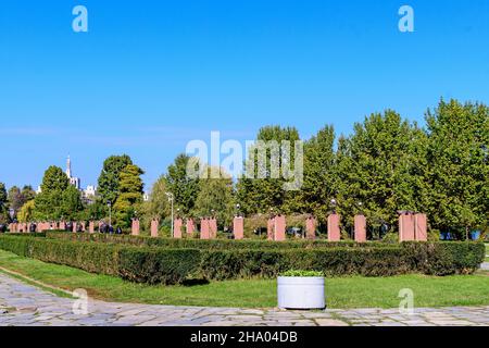 Paesaggio con grandi alberi verdi e lungo vicolo a piedi nel Parco Herastrau a Bucarest, Romania, in una soleggiata giornata autunnale Foto Stock