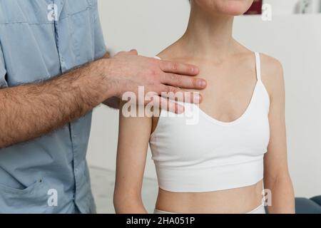 Paziente di sesso femminile in trattamento con collo e spalle osteopatici. Terapista che manipola la schiena della testa e del torace. Una ragazza che riceve il trattamento CST Foto Stock