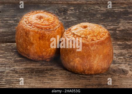 Studio di piccole torte di maiale poggiate su un pannello di legno scuro - John Gollop Foto Stock