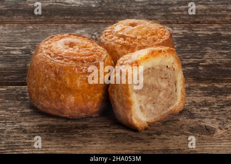 Studio di piccole torte di maiale poggiate su un pannello di legno scuro - John Gollop Foto Stock