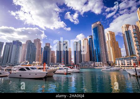 Bella vista dei costosi yacht e motoscafi ormeggiati ai moli del Dubai Marina, circondato da alti grattacieli, Dubai, Emirati Arabi Uniti Foto Stock