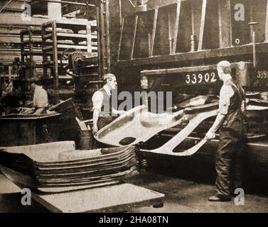Una prima fotografia dei lavoratori che premono le parti della carrozzeria dalla lamiera di un impianto di produzione automobilistico britannico Foto Stock