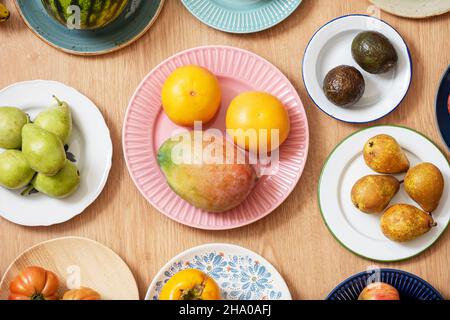 Immagine dall'alto di un set di piatti con frutta assortita, cocomero, pompelmo, manghi africani, avocado maturi, pomodori rosa, pere e banane Foto Stock