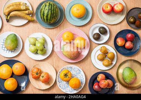 Immagine dall'alto di piatto con frutta assortita, cocomero, pompelmo, manghi africani, avocado maturi, pomodori rosa, pere e banane, mele, persim Foto Stock