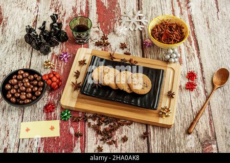 Biscotti al cioccolato su un piatto nero con anice stellato e un asse con colori rosso e bianco. Foto Stock