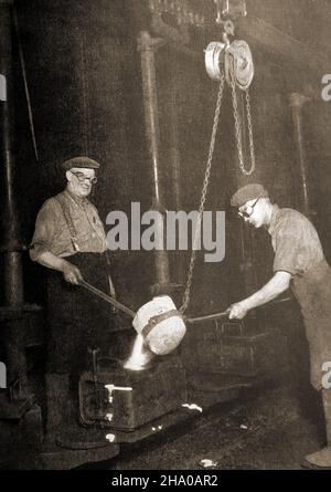 Una vecchia fotografia che mostra i lavoratori di un impianto di produzione di automobili britannico che modellano i blocchi cilindri del motore. Foto Stock