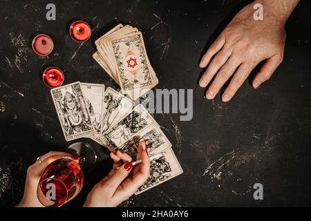 Carte Tarot e le mani femminili di fortuna e cliente su tavola magica nera Foto Stock