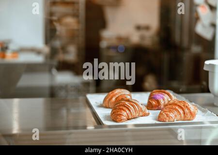 Vassoio con deliziosi croissant freschi in mostra nella panetteria Foto Stock