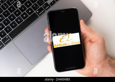 Gruppo Alibaba l'applicazione è aperta nello smartphone. L'uomo sta tenendo un telefono cellulare in mano, l'applicazione aziendale è aperta sullo schermo. Acquisti online sicuri. Novembre 2021, San Francisco, USA Foto Stock