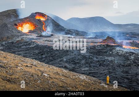 uomo che fotografa caldera vulcanica e lava Foto Stock