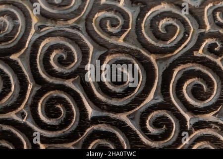 Pannello di legno scuro con ornamento a spirale intagliato, foto da vicino Foto Stock