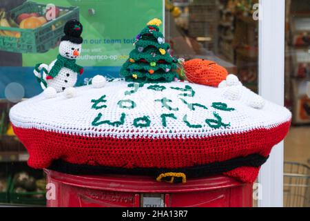 Bombardiere di filato, scena di neve di Natale con l'uomo di neve lavorato a maglia e albero di Natale sulla parte superiore di una casella postale, Regno Unito Foto Stock