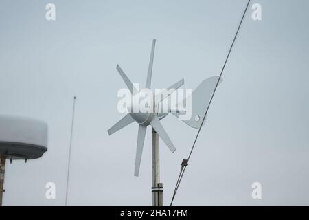 Turbina del generatore di vento sulla barca a vela ormeggiata nel porto Foto Stock
