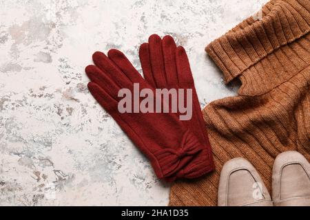 Guanti caldi, maglione e scarpe su sfondo grunge, primo piano Foto Stock