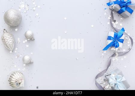 Bellissimi confetti con palle di Natale e regali su sfondo grigio Foto Stock