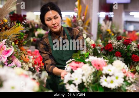 Fiorista femminile asiatico esamina i mazzi in un negozio di fiori Foto Stock