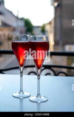 Bere del Kir Royal, aperitivo francese a base di creme de cassis con champagne, tipicamente servito in calici di flauto, con vista sul vecchio Foto Stock