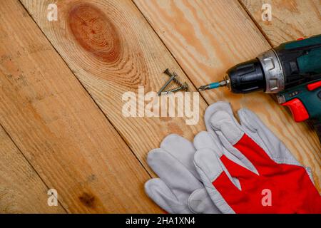 un cacciavite e guanti di costruzione si trovano sul pavimento di legno.lavori di costruzione. Foto Stock