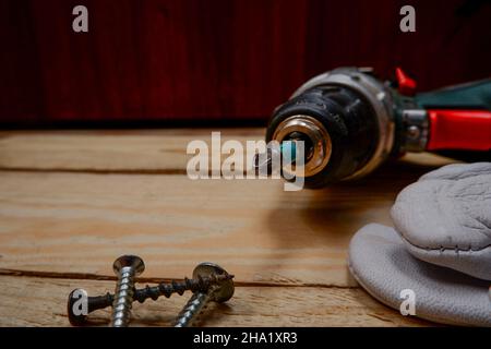 un cacciavite e guanti di costruzione si trovano sul pavimento di legno.lavori di costruzione. Foto Stock