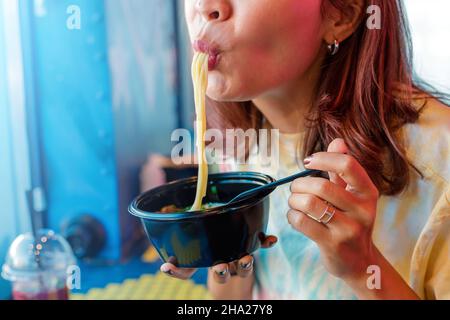 Donna asiatica felice mangiare ramen noodle zuppa nel ristorante fast food Foto Stock