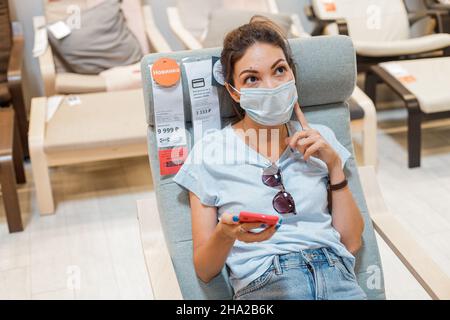 14 giugno 2021, Ufa, Russia: La donna in maschera si sedette su una sedia e pensò all'acquisto in un negozio IKEA Foto Stock