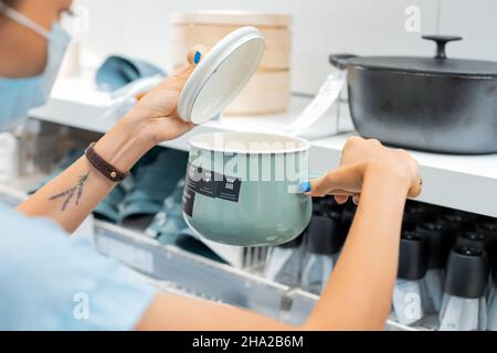 14 giugno 2021, Ufa, Russia: Casalinga donna in maschera protettiva durante il covid pandemic shopping per pentola di cottura nel mercato IKEA Foto Stock