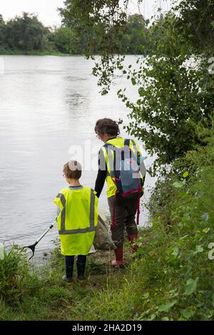 Operazione di pulizia del fiume Garonna a Blagnac, il 18 settembre 2021. Madre e suo figlio, donna e bambino che indossano gilet gialli fluorescenti piccone Foto Stock