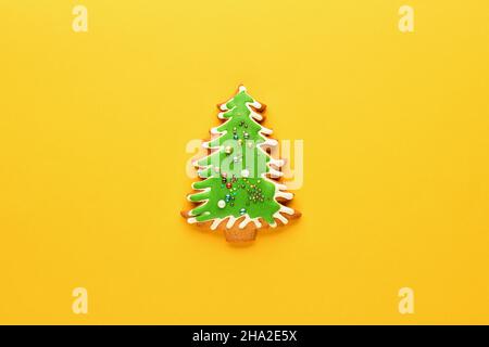 Albero di Natale su sfondo giallo. Pan di zenzero a forma di albero di Natale. Nuovo anno e sfondo di Natale. Disposizione piatta Foto Stock