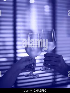 Coppia giovane con due bicchieri di vino bianco a letto sullo sfondo sfocato. Spazio di copia. Colore di 2022 anni, molto peri, tonico Foto Stock