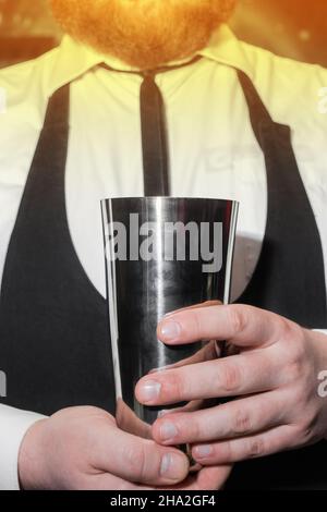 Le mani di un barista professionista possono contenere uno strumento per mescolare e preparare cocktail shaker. Foto Stock