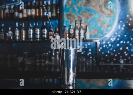 Utensile in metallo per la cottura e l'agitazione di cocktail alcolici shaker con cucchiaio da bar sul banco bar. Foto Stock