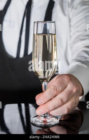 Un barista professionista serve champagne ghiacciato frizzante con gas in bicchiere al bar. Foto Stock