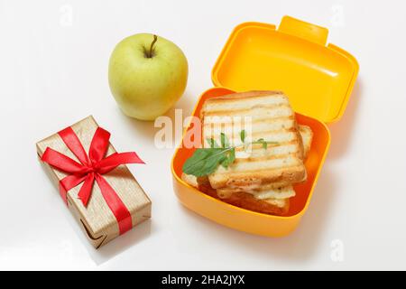 Pranzo al sacco giallo con fette tostate di pane, formaggio e mela verde. Foto Stock