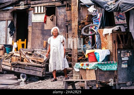 Vecchia signora in alloggio slum e la città timosa a Tondo, Manila centrale, Filippine Foto Stock