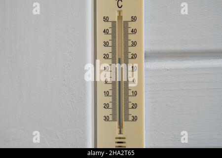 Termometro su una parete bianca in legno che mostra la temperatura esterna in gradi celsius Foto Stock