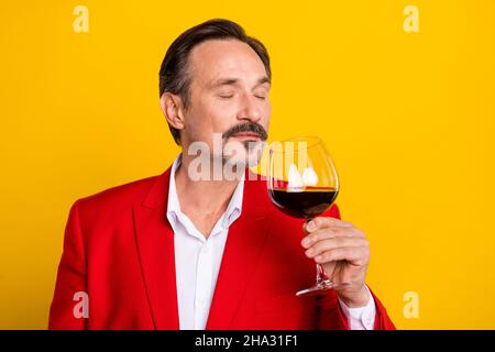 Ritratto di bel buon umore uomo tranquillo odore di vino gustoso aroma isolato su sfondo di colore giallo Foto Stock