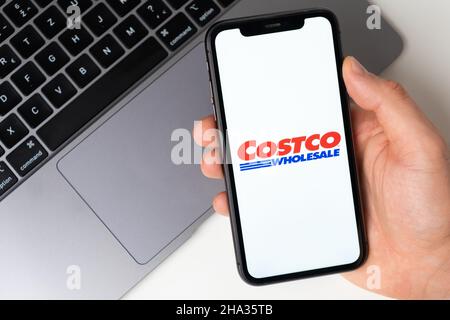 Applicazione mobile Costco Wholesale sullo schermo dello smartphone. Fai acquisti mentre sei seduto a casa utilizzando un'app mobile o un notebook. Uno smartphone in una mano di un uomo. Novembre 2021, San Francisco, USA Foto Stock