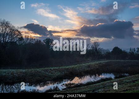 Tramonto su un laghetto di gestione delle acque piovane accanto ad un nuovo sviluppo abitativo, Oaklands Park, Ashbourne, Derbyshire Foto Stock