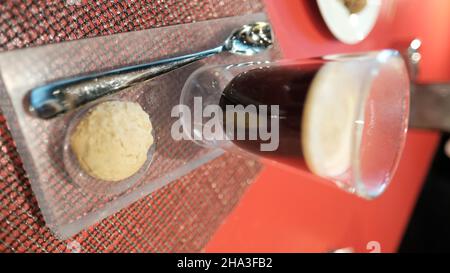 Caffè e un biscotto su un vassoio su un tavolo rosso W Bangkok Foto Stock