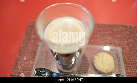 Caffè e un biscotto su un vassoio su un tavolo rosso W Bangkok Foto Stock
