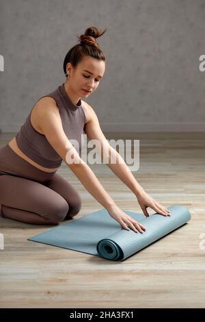 Donna incinta sorridente in abbigliamento sportivo pronto per la ginnastica mattutina o l'esercizio fisico. Giovane donna felice seguire stile di vita sano durante la gravidanza, tenere yoga Foto Stock