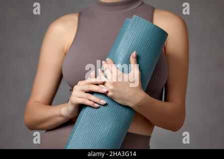 Donna incinta sorridente in abbigliamento sportivo pronto per la ginnastica mattutina o l'esercizio fisico. Giovane donna felice seguire stile di vita sano durante la gravidanza, tenere yoga Foto Stock