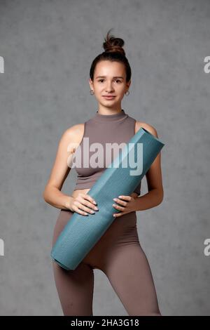 Donna incinta sorridente in abbigliamento sportivo pronto per la ginnastica mattutina o l'esercizio fisico. Giovane donna felice seguire stile di vita sano durante la gravidanza, tenere yoga Foto Stock