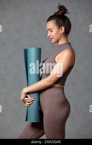 Donna incinta sorridente in abbigliamento sportivo pronto per la ginnastica mattutina o l'esercizio fisico. Giovane donna felice seguire stile di vita sano durante la gravidanza, tenere yoga Foto Stock